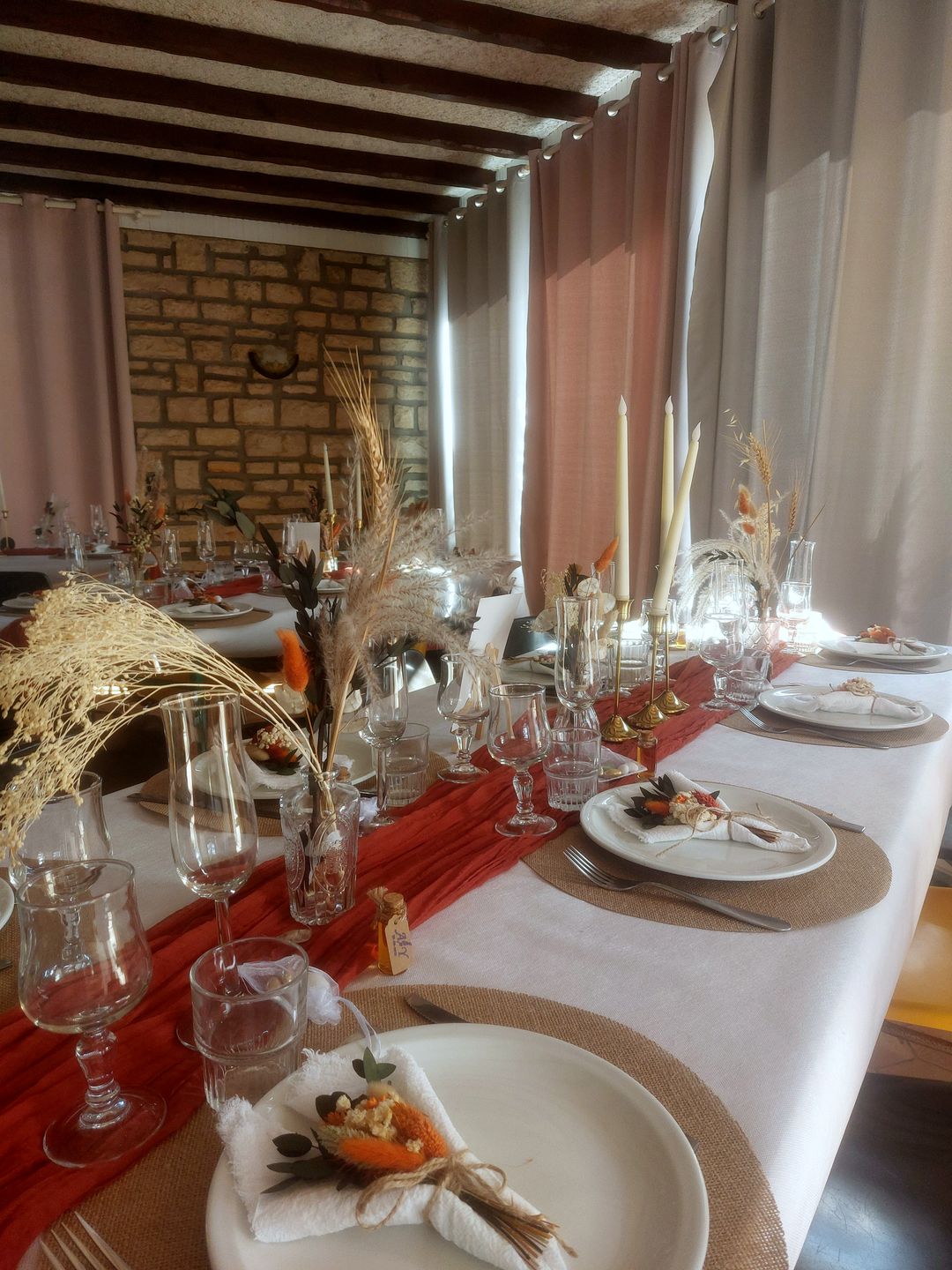 Longue table de réception dressée avec bougies et fleurs séchées