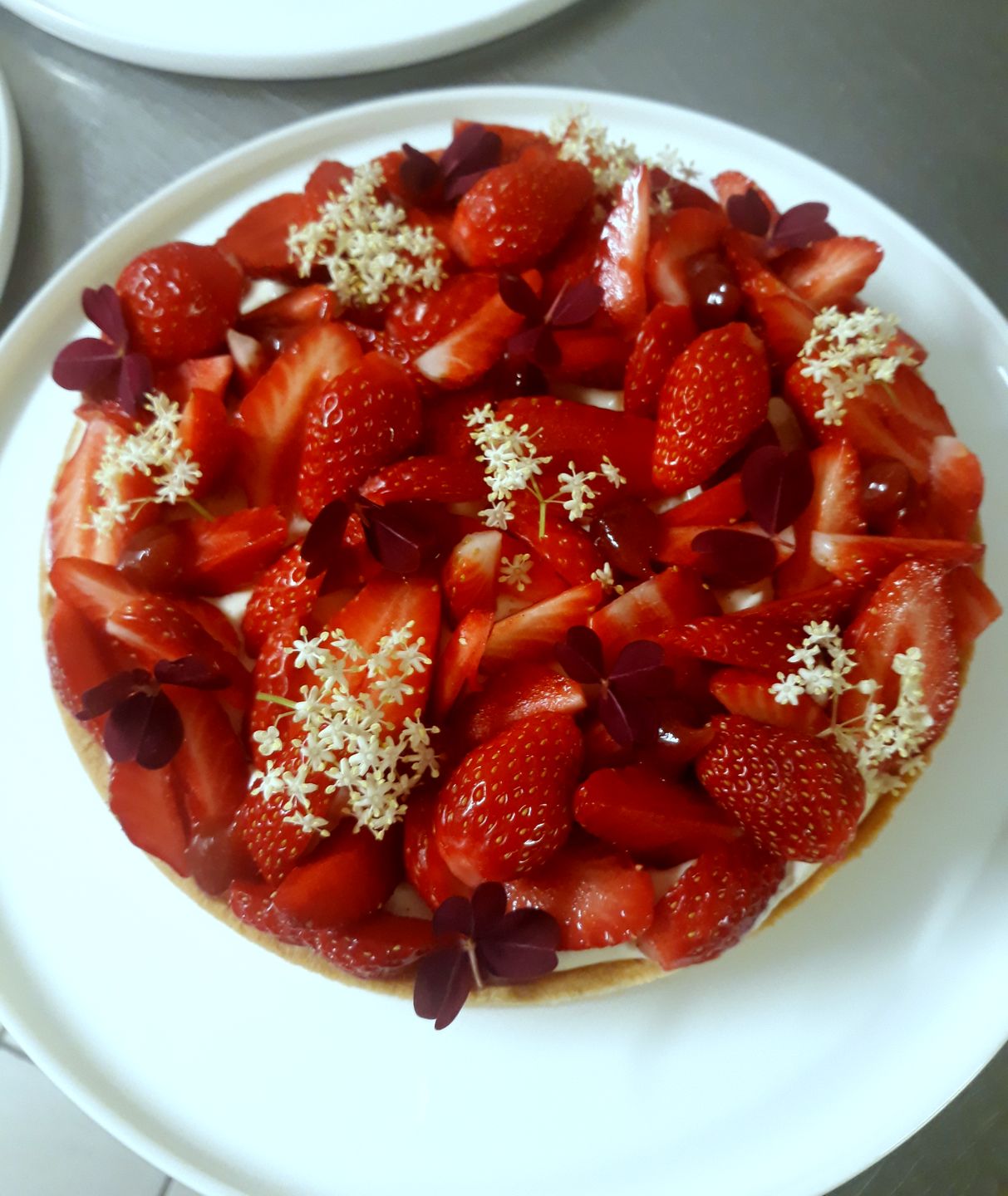 Tarte aux fraises décorée de fleurs de sureau et de feuilles d'oxalis